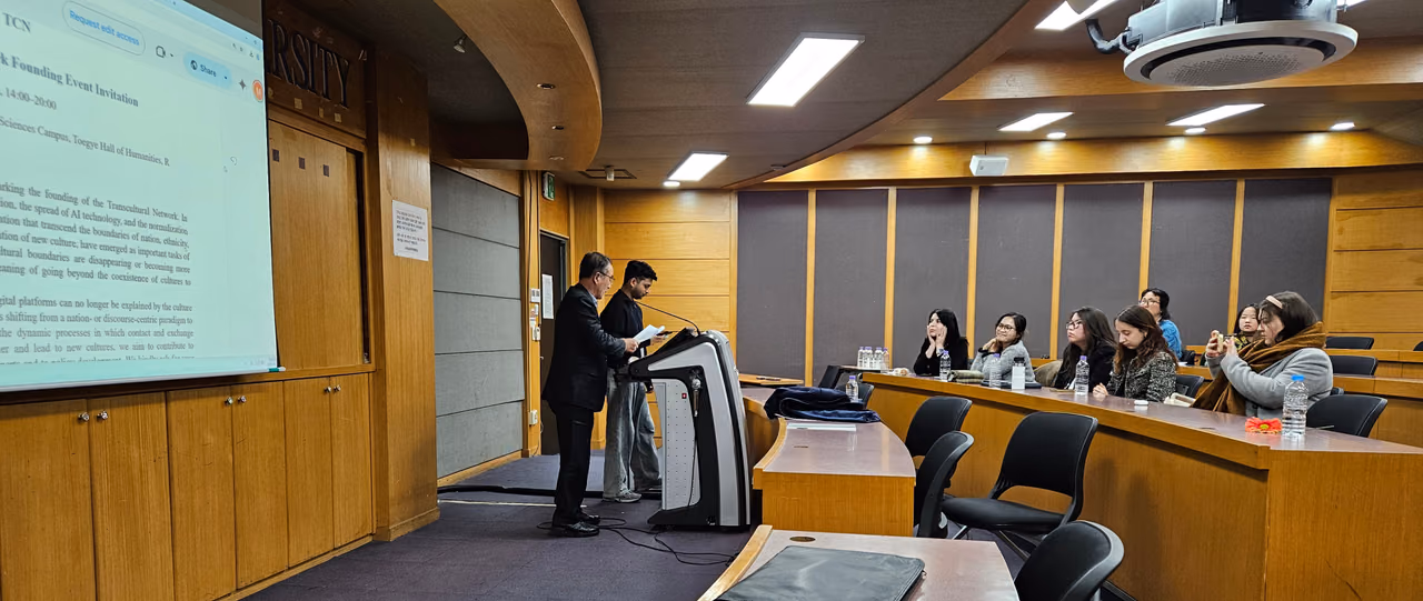Two speakers at the lectern as the founding invitation is projected onto the screen of the lecture hall