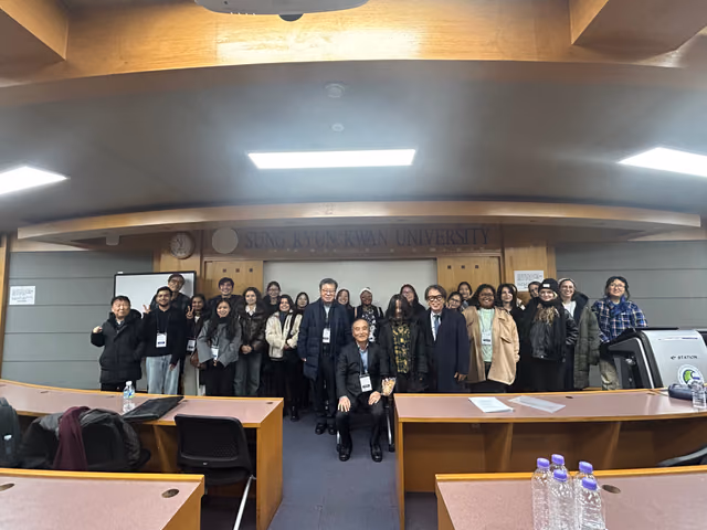 Group photograph of members and guests in the lecture hall beneath the Sungkyunkwan University lettering